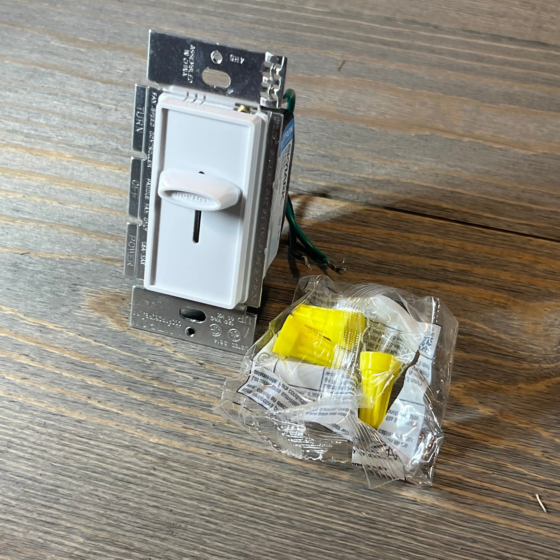 White Lutron Skylark fan control with installation kit on wooden surface.