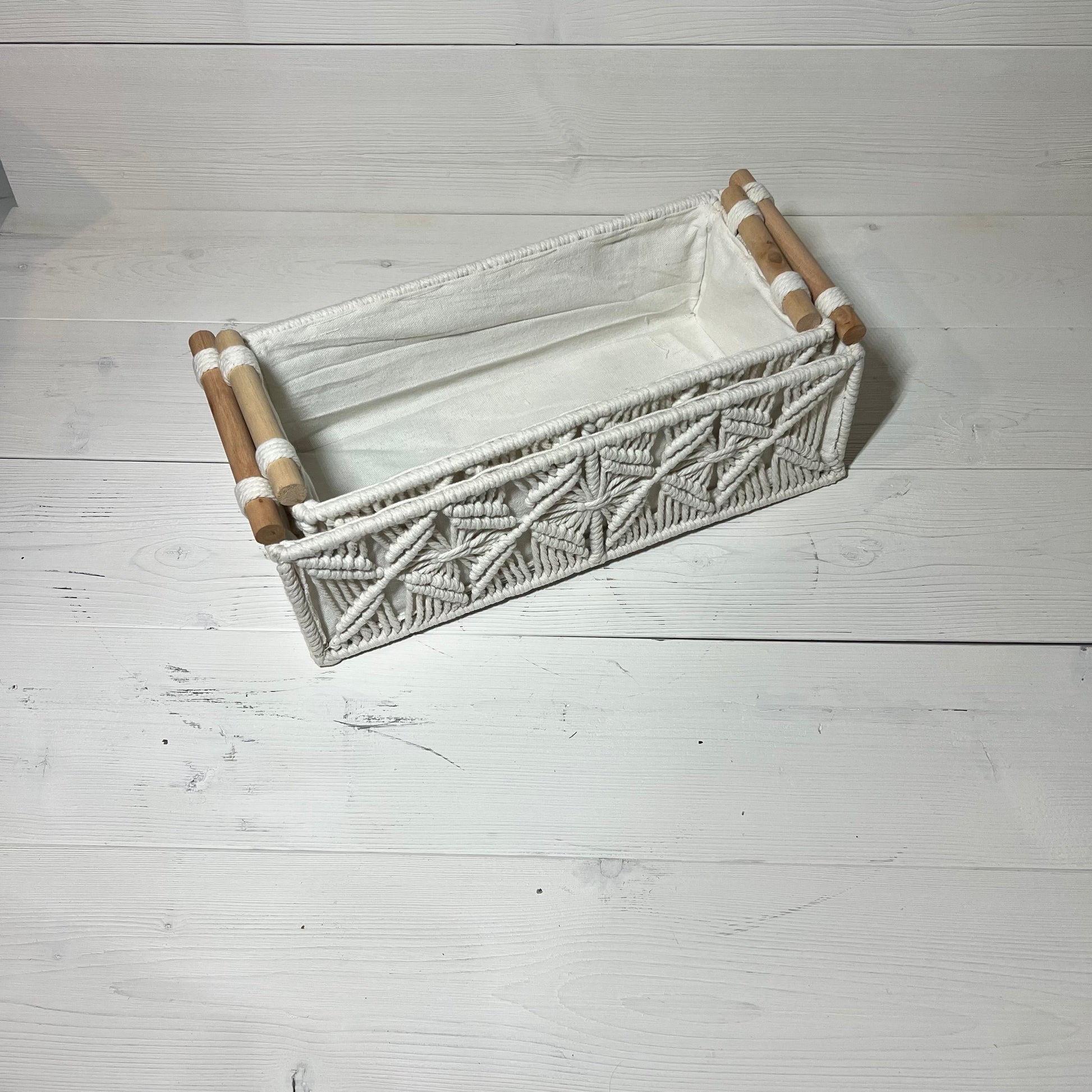 Handwoven macrame storage basket in ivory white with wooden handles, ideal for bathroom or bedroom decor. Bohemian style organizer.