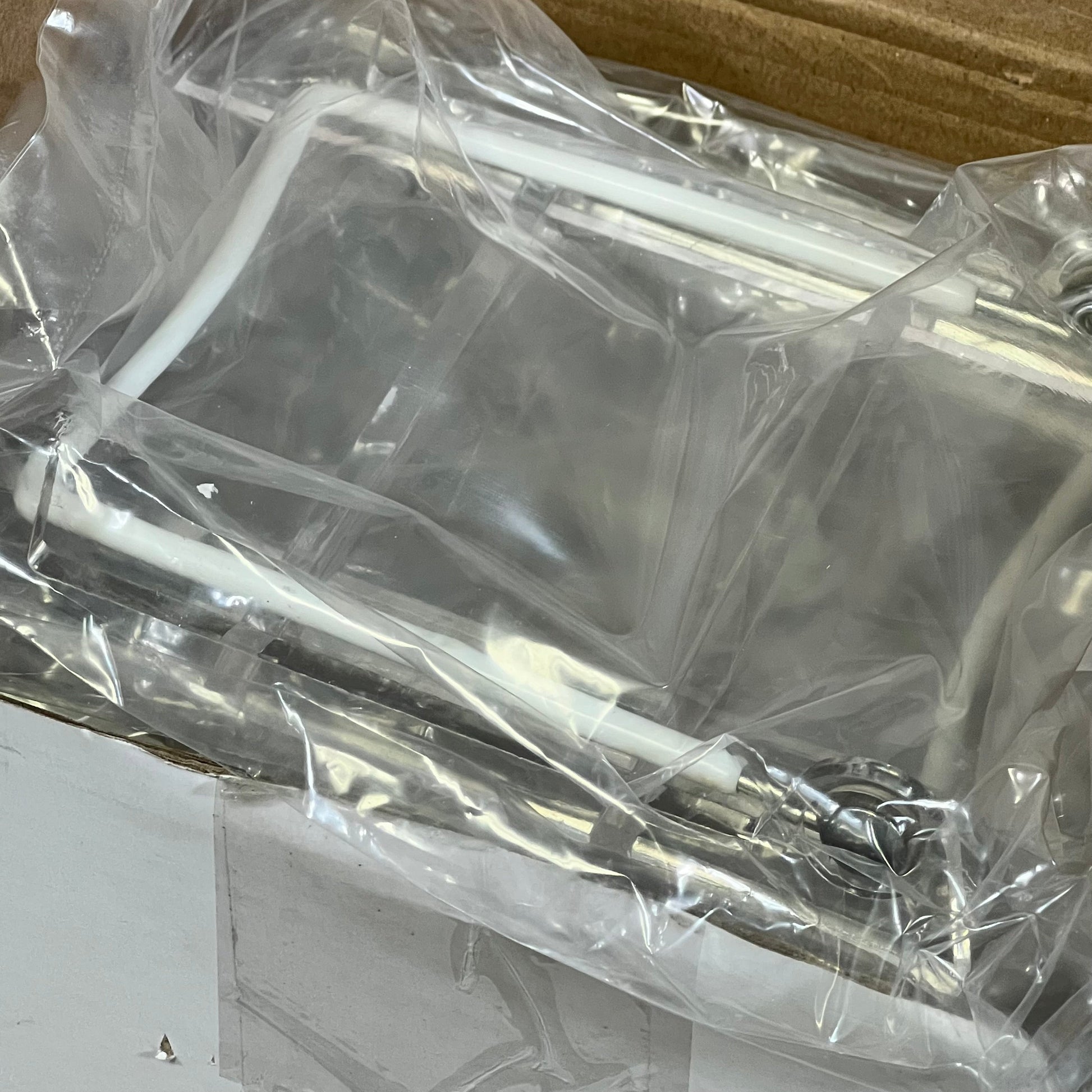 Clear acrylic plate stand packaged with adjustable white wire for secure display of plates and books.