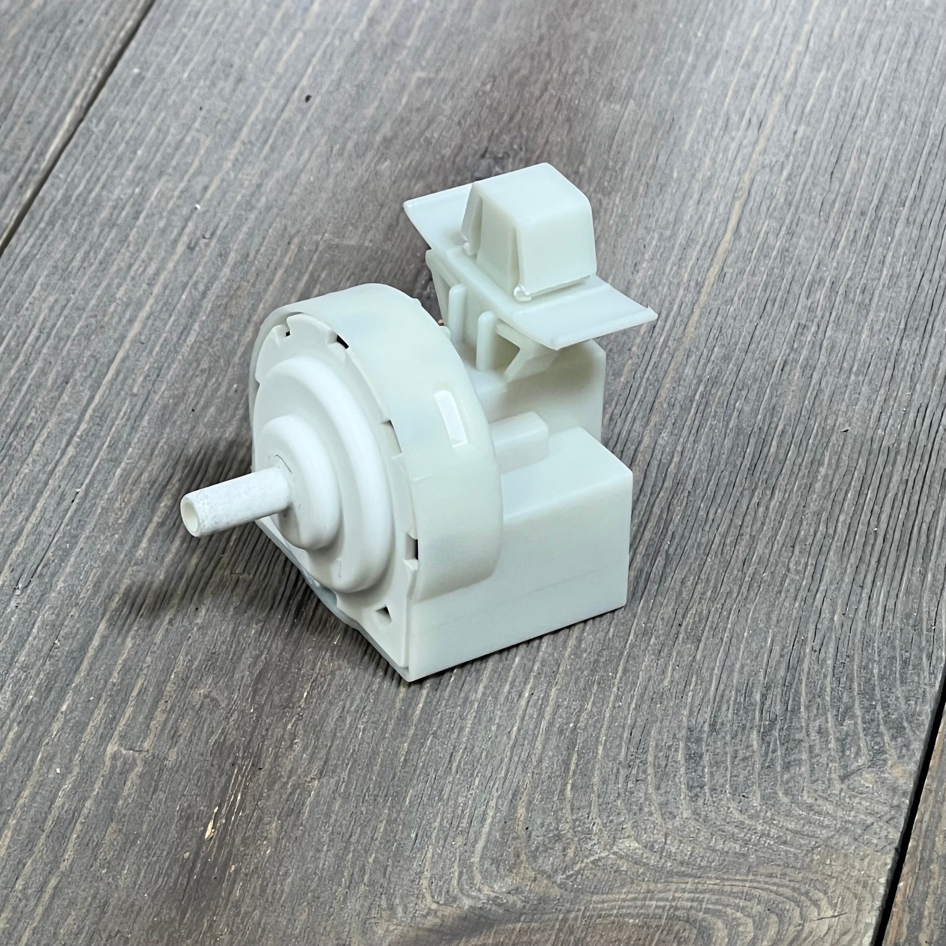Whirlpool washer pressure switch W11316246, showing detailed design on wooden surface.