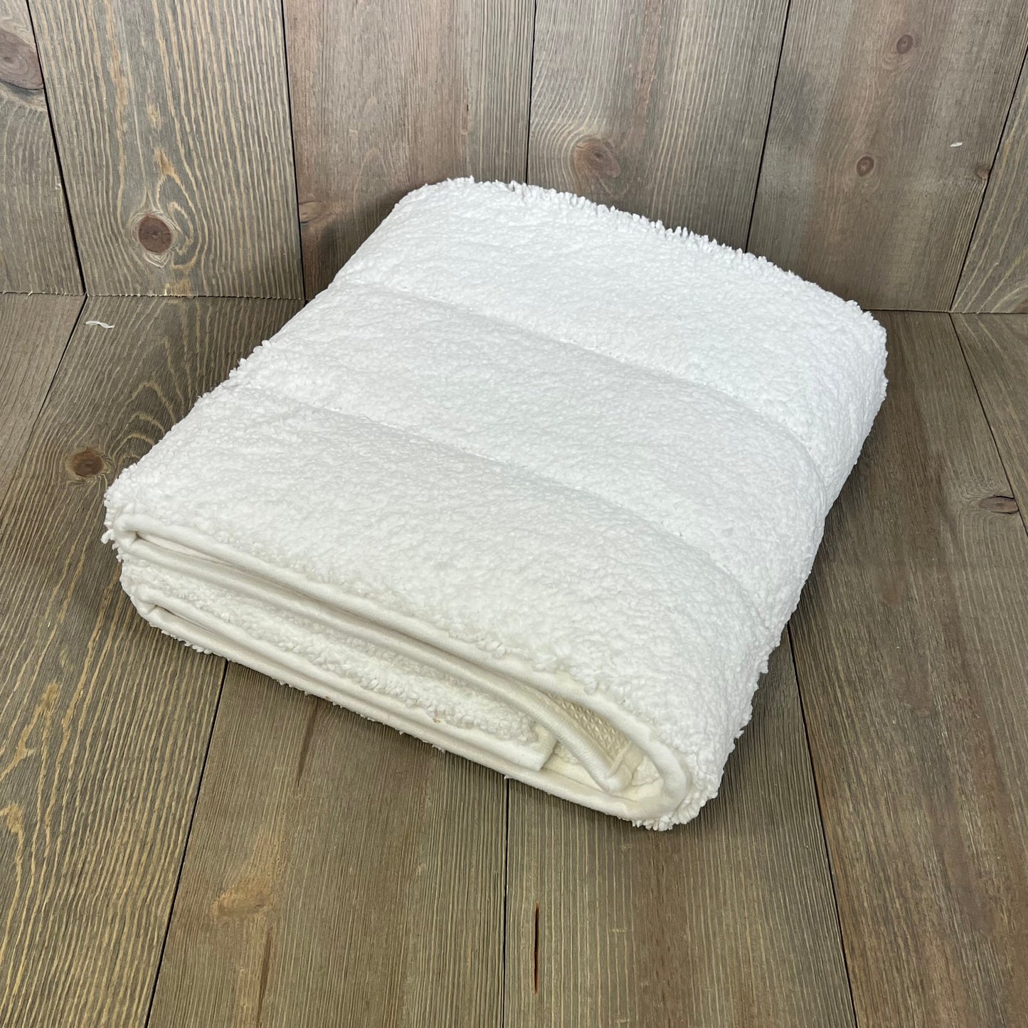 Folded DEXI bathroom rug 43x24, showcasing its soft, absorbent microfiber and non-slip rubber backing on a wooden floor.