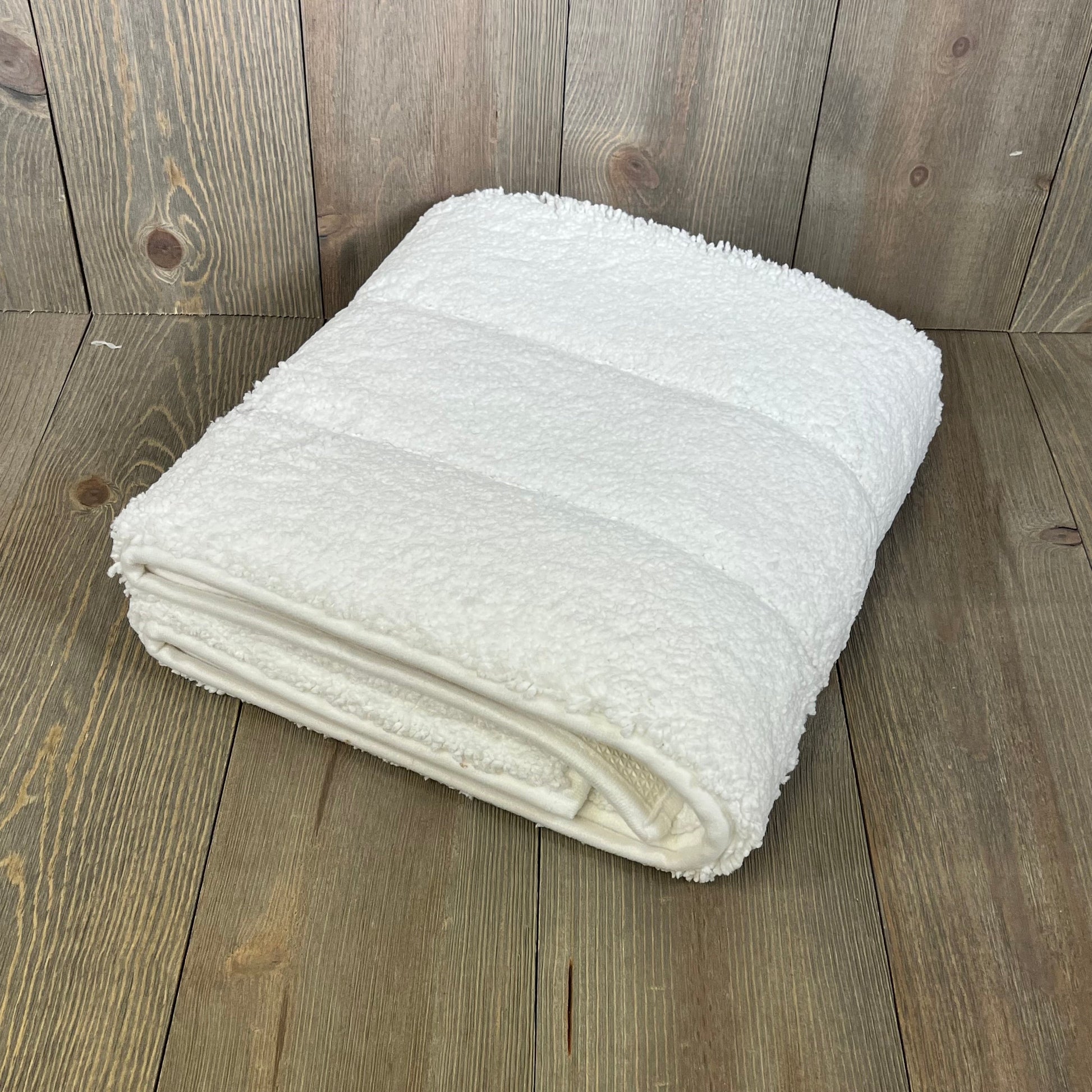 Folded DEXI bathroom rug 43x24, showcasing its soft, absorbent microfiber and non-slip rubber backing on a wooden floor.