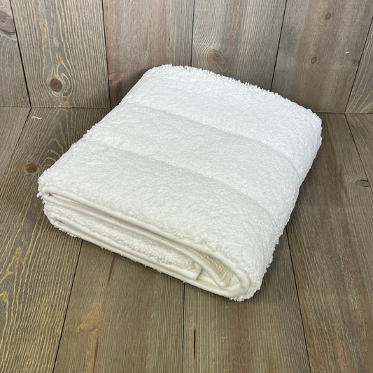 Folded DEXI bathroom rug 43x24, showcasing its soft, absorbent microfiber and non-slip rubber backing on a wooden floor.