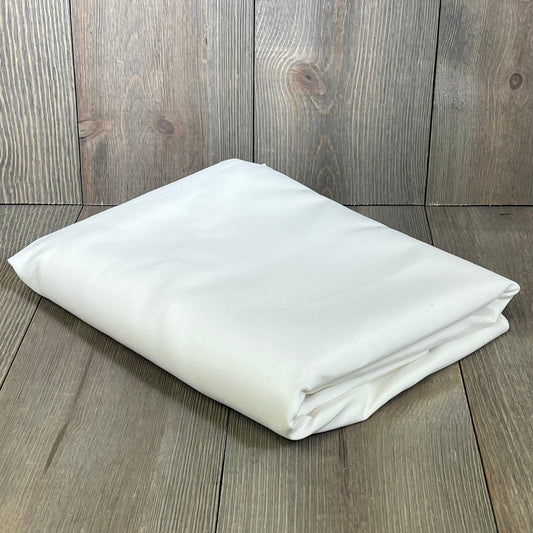 Folded white oval tablecloth on wooden background, showcasing rustic faux linen texture, ideal for farmhouse dining.