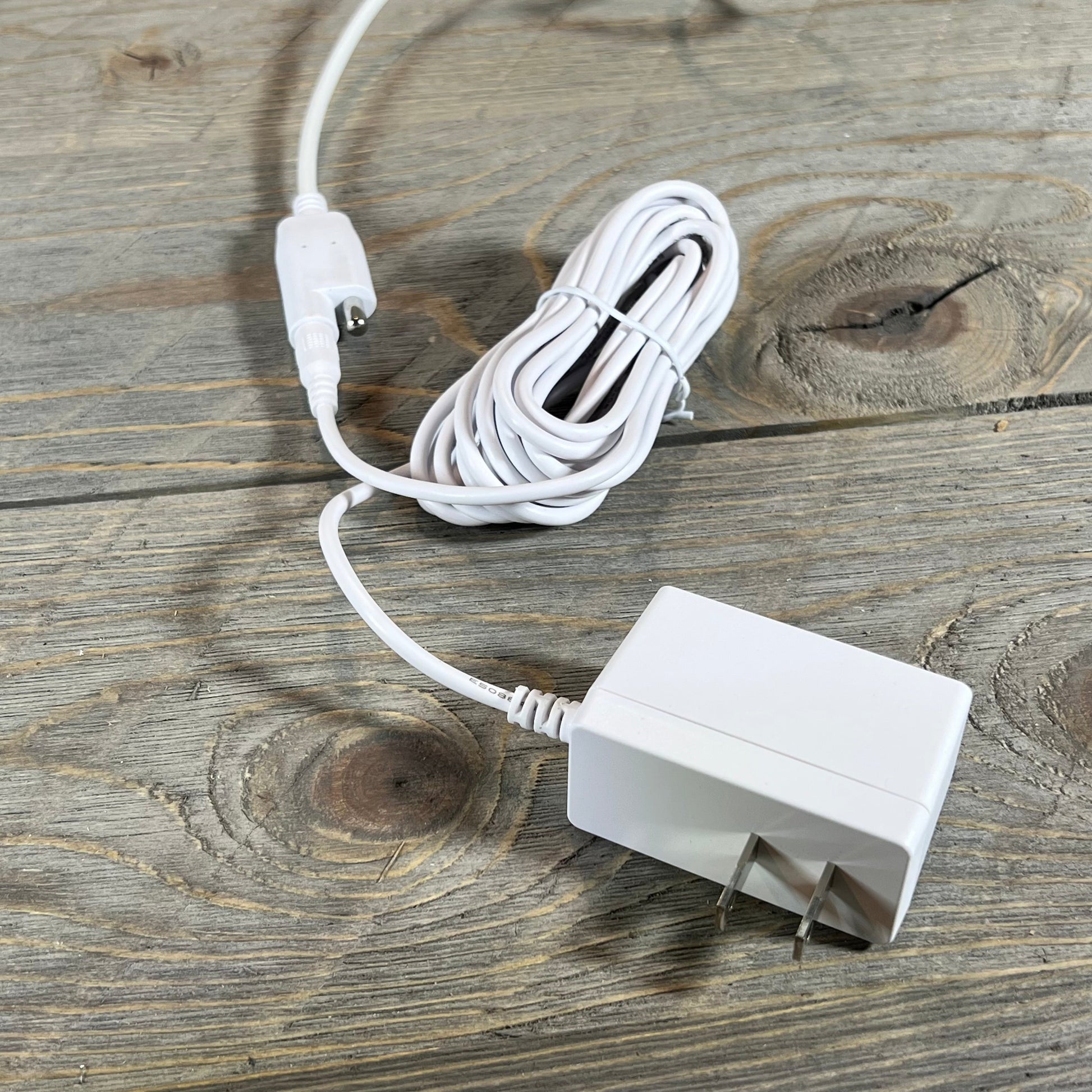 White power adapter and coiled cable for Smart Register Booster Fan on wooden surface.