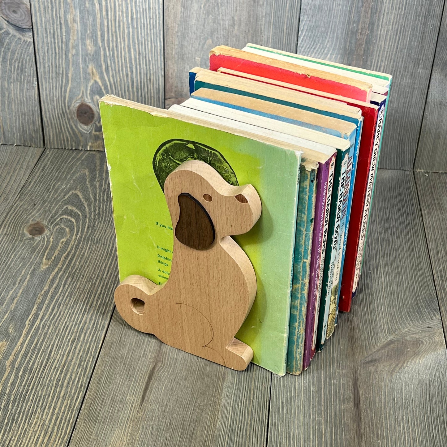 Decorative wooden puppy dog bookends holding colorful books on wooden shelf, ideal for kids' rooms or office decor.